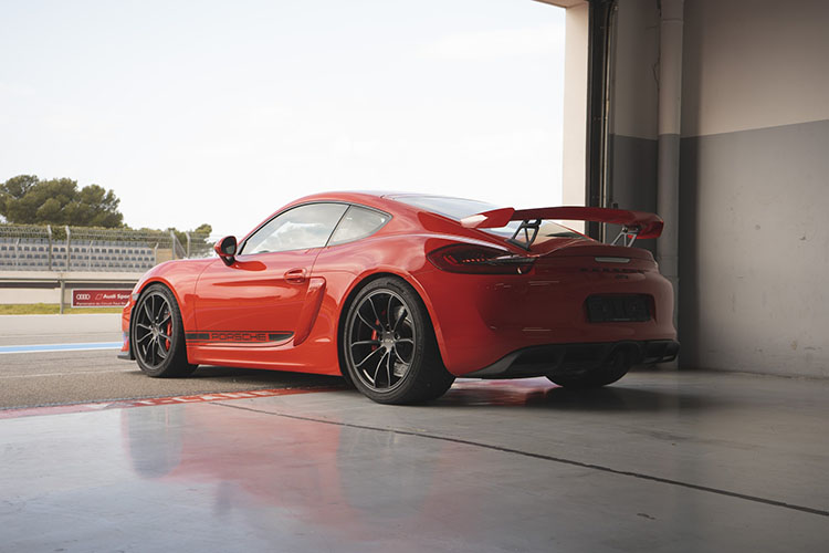 Red Porsche Cayman at the track in a garage